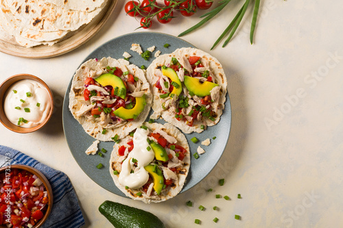 Mini tortillas with tomato salsa, avocado and boiled chicken. Top view.