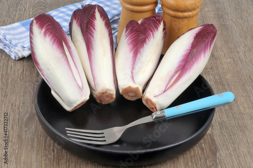 Fotografia Endives bicolores dans une assiette noire avec une fourchette en gros plan