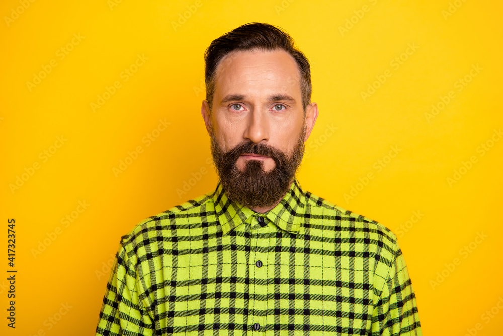 Close-up portrait of attractive serious content man wearing checked shirt isolated over bright yellow color background Close-up portrait of attractive serious content man wearing checked shirt isolated over bright yellow color background