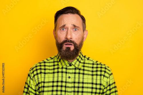 Portrait of attractive miserable unlucky devastated man wearing checked shirt isolated over bright yellow color background