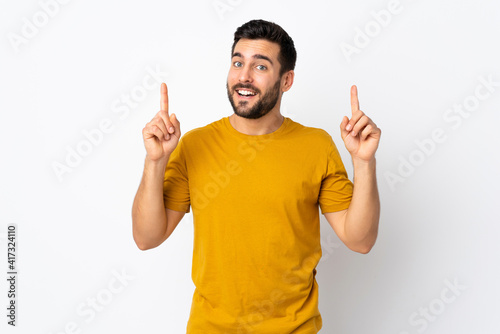 Young handsome man with beard isolated on white background pointing up a great idea