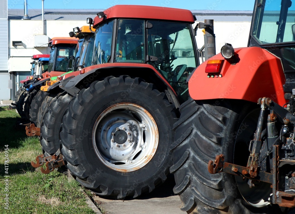 Back view of large agricultural tractors, lined up outside the farm building. Back view of large agricultural tractors, lined up outside the farm building.