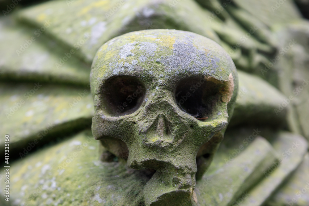 An old sculpture of a human skull on a grave to depict death, the end of life. An old sculpture of a human skull on a grave to depict death, the end of life.