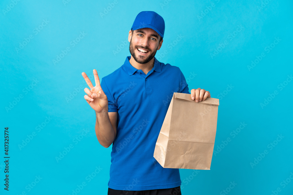 Delivery man with beard isolated on blue background smiling and showing victory sign Delivery man with beard isolated on blue background smiling and showing victory sign