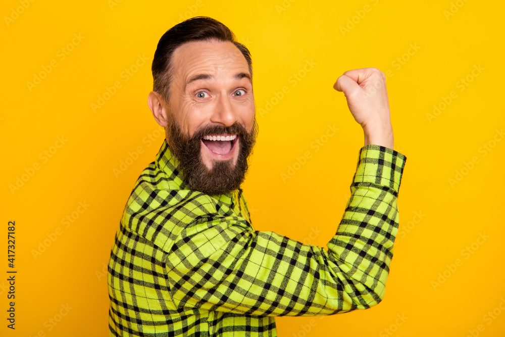 Profile side photo of excited man happy positive smile rejoice win victory fists hand isolated over yellow color background Profile side photo of excited man happy positive smile rejoice win victory fists hand isolated over yellow color background