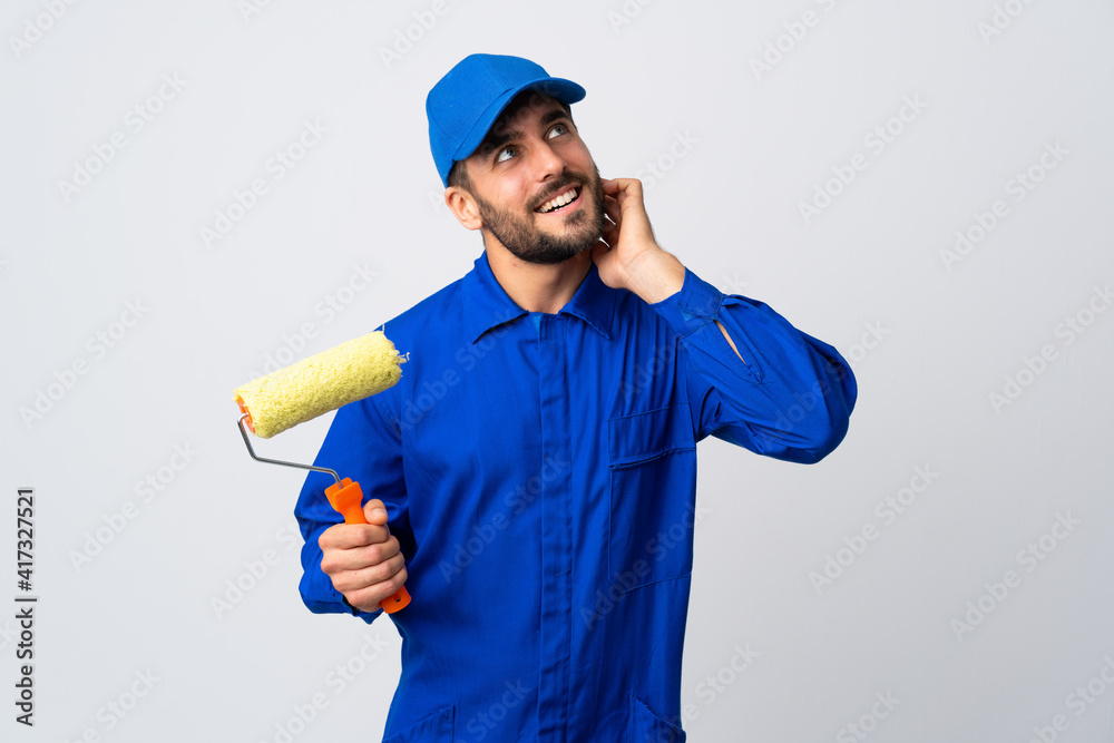 Painter man holding a paint roller isolated on white background thinking an idea