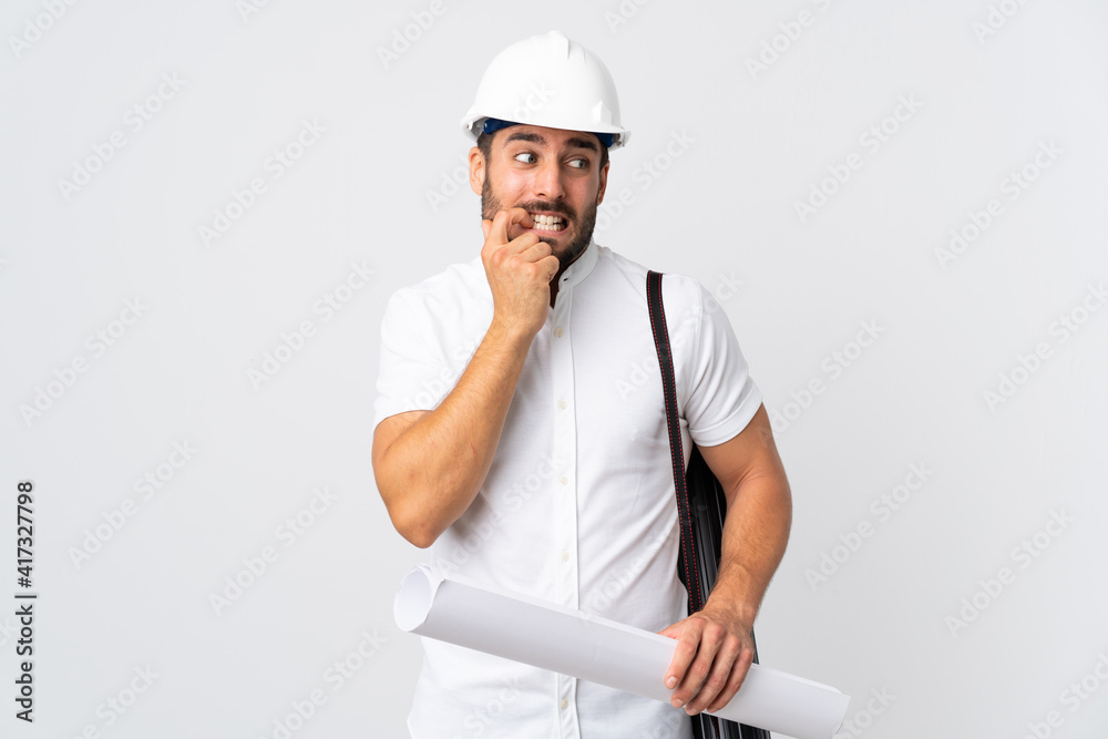 Young architect man with helmet and holding blueprints isolated on white background nervous and scared Young architect man with helmet and holding blueprints isolated on white background nervous and scared
