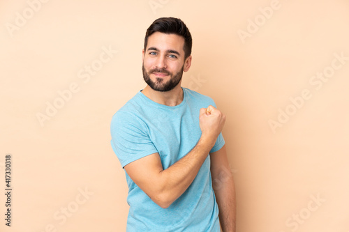 Caucasian handsome man isolated on beige background proud and self-satisfied