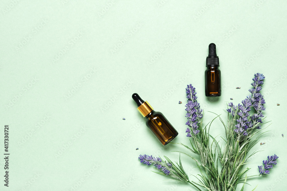 Lavender essential oil on mint green background. Aromatherapy treatment and Skincare spa cosmetics concept Lavender essential oil on mint green background. Aromatherapy treatment and Skincare spa cosmetics concept