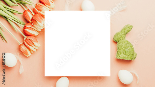 Easter card. Golden  white colour egg in basket with spring tulips  feathers on pastel pink background in Happy Easter decoration. Flat lay  top view with copy space.