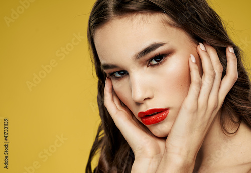 Woman with red lips touches her face with the hands of the Copy Space model
