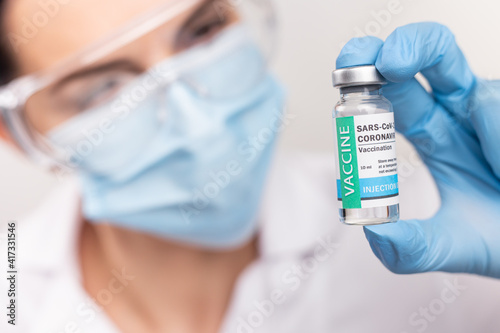SARS - CoV2 Vaccination concept. Close up COVID-19 vaccine dose. A doctor or nurse in a laboratory holds a vial with a vaccine. Pandemic immunity photo