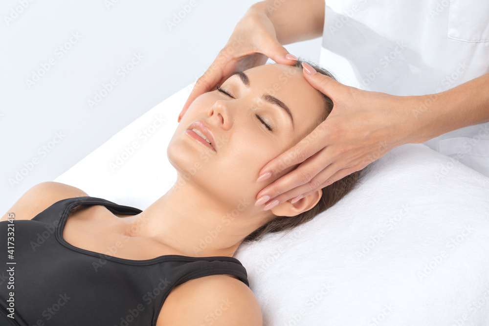 Masseur makes a relaxing massage on the face, neck, shoulders and collarbones of a young beautiful woman in a spa. Cosmetology and massage concept. Masseur makes a relaxing massage on the face, neck, shoulders and collarbones of a young beautiful woman in a spa. Cosmetology and massage concept.