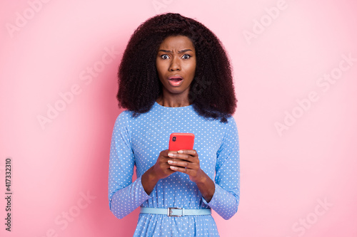 Photo of speechless lady hold phone look camera open mouth wear blue dotted dress isolated pink color background