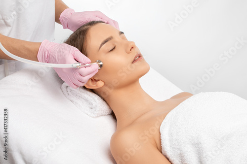 The cosmetologist makes the procedure Microdermabrasion of the face skin of a beautiful girl in a beauty salon.Cosmetology and professional skin care.
