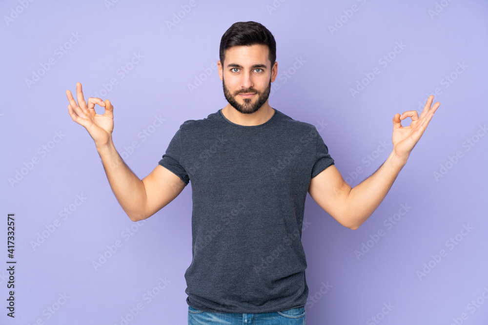 Caucasian handsome man in zen pose over isolated purple background Caucasian handsome man in zen pose over isolated purple background