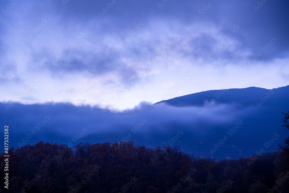 Mountains in the clouds against the blue twilight sky
