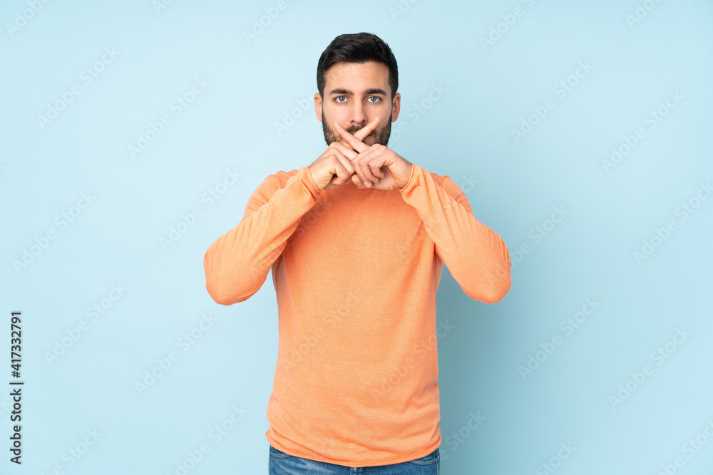 Naklejka premium Caucasian handsome man showing a sign of silence gesture over isolated blue background