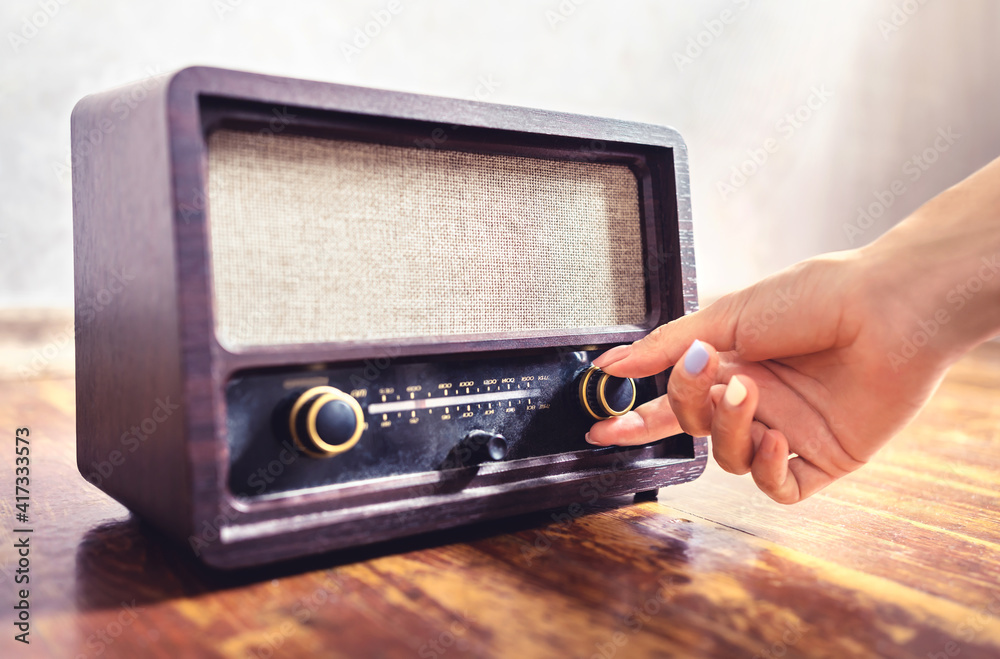 Retro radio tuning. Woman using old vintage music equipment. Adjusting volume or frequency tuner knob. Turning on or off stereo receiver or speaker. Changing channel or station with dial button. - obrazy, fototapety, plakaty 
