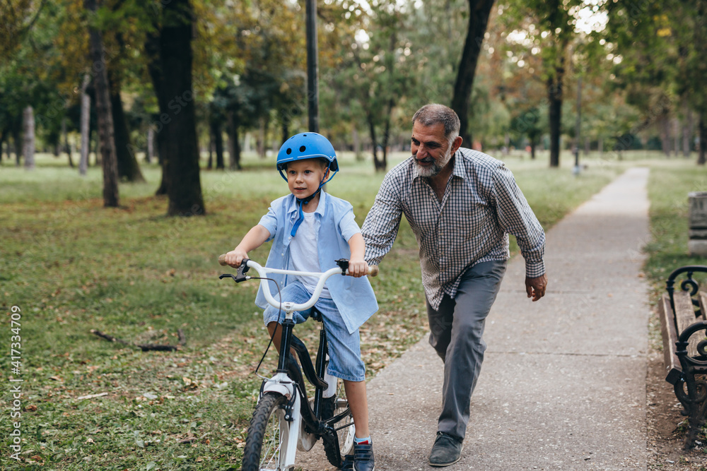 grandfather and grandson riding a bike in public park