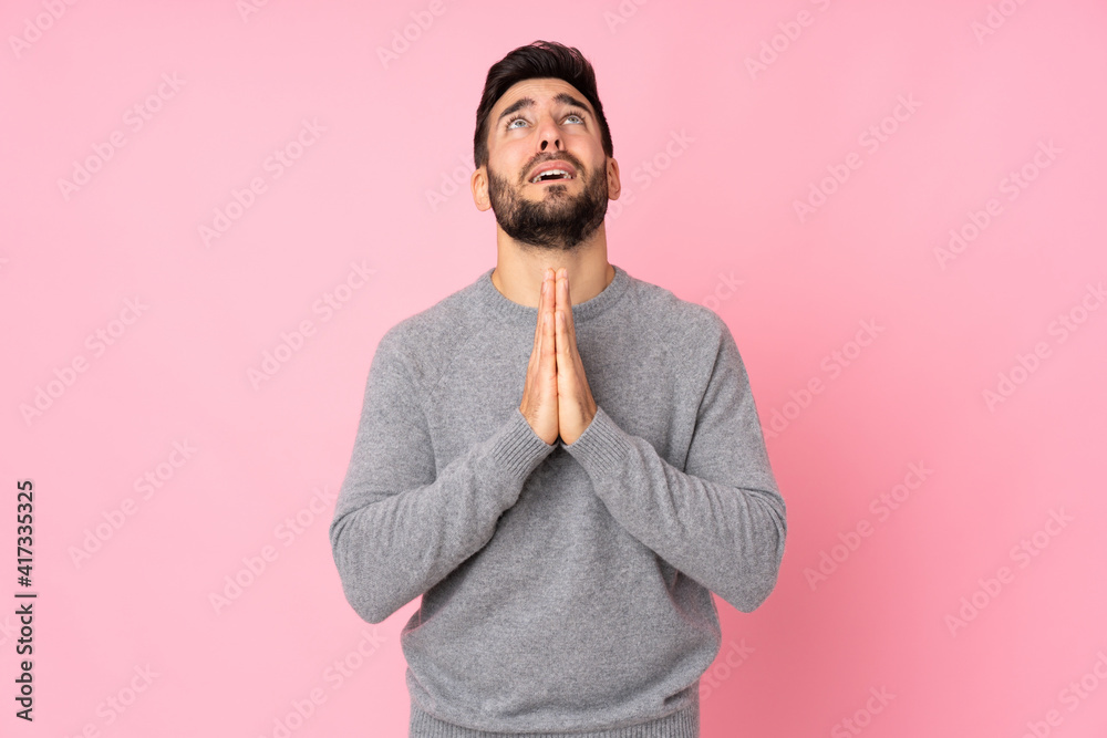 Caucasian handsome man over isolated background keeps palm together. Person asks for something Caucasian handsome man over isolated background keeps palm together. Person asks for something