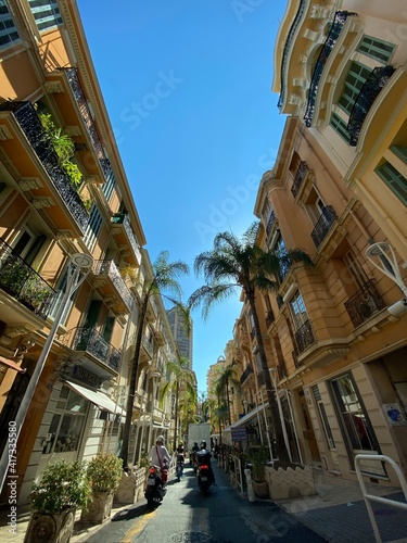 Fototapeta Naklejka Na Ścianę i Meble -  Enge Gasse in Monaco mit Palmen bei Sonnenschein 
und Blauem Himmel, Monte-Carlo, Roller 