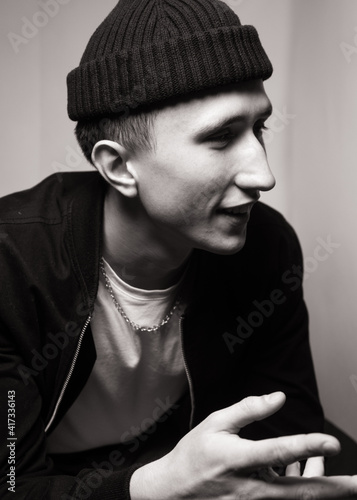 portrait of smiling young  man  wearing black knit hat. Black and white studio shot on white background. Teenagerhood.