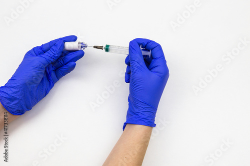 hands in medical blue gloves with a syringe and a vaccine on a white background