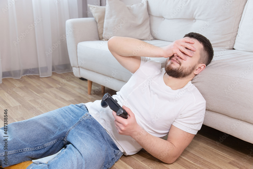 young sad  man in headset  playing video games and loose, life at home. Technology, gaming, entertainment concept.