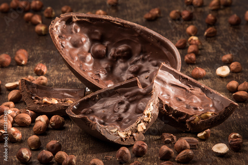 Quadro su tela Cracked stuffed chocolate easter egg on a wooden table with hazelnuts