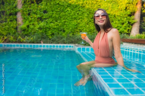 Portrait young asian woman relax happy smile around swimming pool in hotel