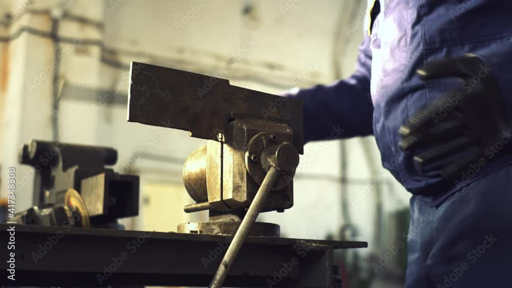 Car mechanic using wrench to repair the engine, car service.Repair of spare parts for trucks.Metal clamps for clamping.The metal part is clamped in a vise on the workbench. Close-up Car mechanic using wrench to repair the engine, car service.Repair of spare parts for trucks.Metal clamps for clamping.The metal part is clamped in a vise on the workbench. Close-up