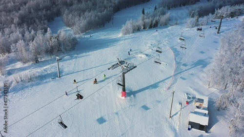 Aerial: ski resort on sunny day, people activity on mountain slope photo