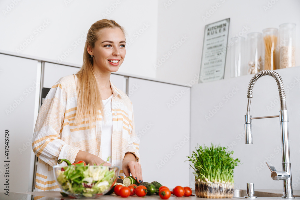 Joyful blonde woman smiling while preparing fresh salad Joyful blonde woman smiling while preparing fresh salad
