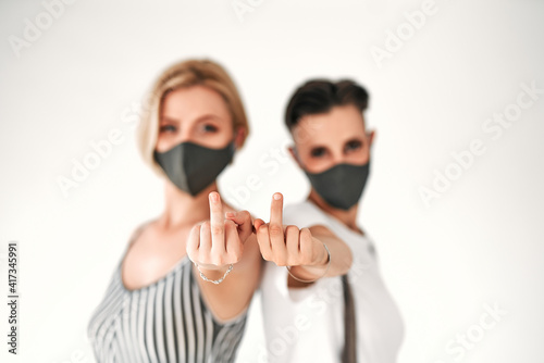 Konstfotografi Two women in a medical mask with middle finger fuck sign hand gesture, coronavirus protection