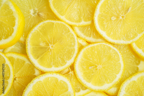 Fruit background, top view. Juicy yellow lemon cut into round slices.