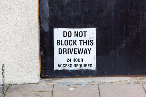 A sign on a garage stating do not block this driveway, in constant use