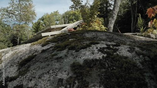 Reveal of a beautiful cottage from behind a large boulder in the front yard of the Le Belvédère events center in Wakefield, Quebec. photo