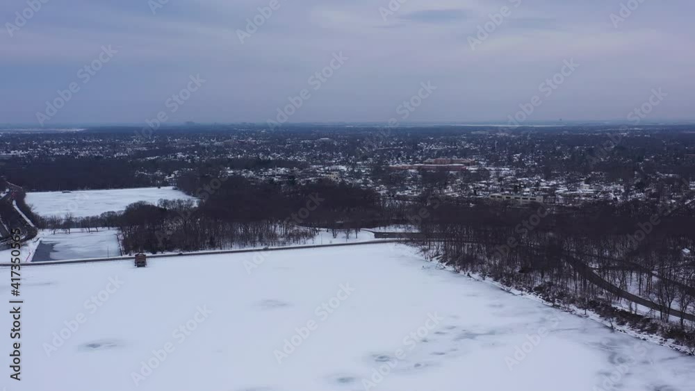 An aerial view from a drone, over a long lake during sunrise on a cloudy morning. The camera dolly in and pan left slightly over the snow covered, frozen lake below. An aerial view from a drone, over a long lake during sunrise on a cloudy morning. The camera dolly in and pan left slightly over the snow covered, frozen lake below.