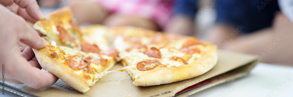 On table lies pizza, cut into pieces man's hand holds two piles. Cooking pizza at home concept On table lies pizza, cut into pieces man's hand holds two piles. Cooking pizza at home concept