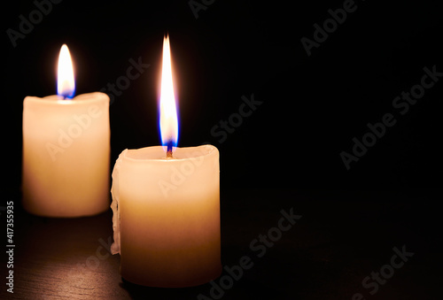 Two burning candles on the table in night dark. Flame of the hope and memory. Close up view with copy space.