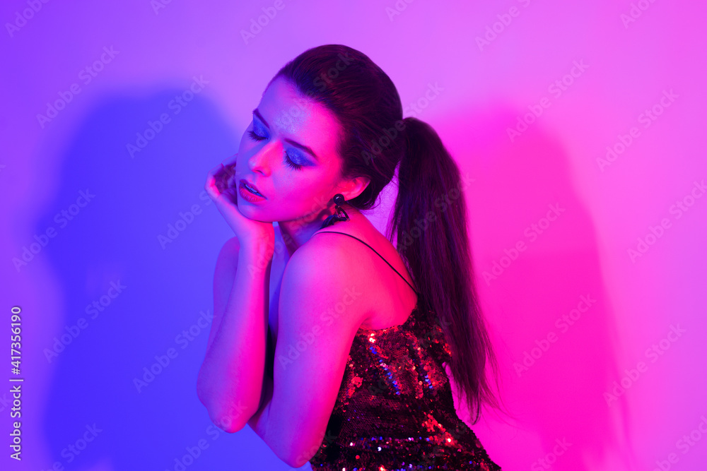 A girl in neon is dancing against a red-blue background. Hipster girl with fashionable haircut and glasses dancing, posing. Model in a fur coat at the club. A girl in neon is dancing against a red-blue background. Hipster girl with fashionable haircut and glasses dancing, posing. Model in a fur coat at the club.