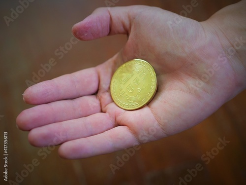 A man hold a golden coin of bitcoin(BTC). A cryptocurrency made by Satoshi Nakamoto