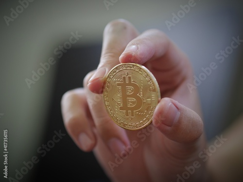 A man hold a golden coin of bitcoin(BTC). A cryptocurrency made by Satoshi Nakamoto