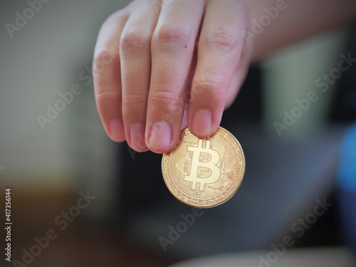A man hold a golden coin of bitcoin(BTC). A cryptocurrency made by Satoshi Nakamoto