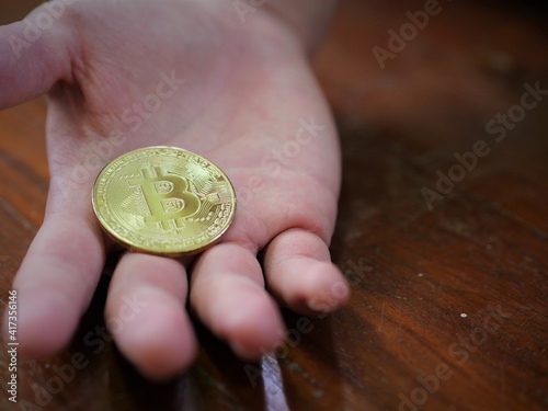 A man hold a golden coin of bitcoin(BTC). A cryptocurrency made by Satoshi Nakamoto