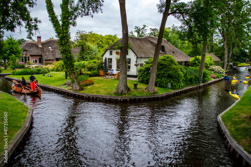 Giethoorn, Netherlands - July 6, 2019: People paddling boats on the canals of Giethoorn village, known as the Venice of the Netherlands