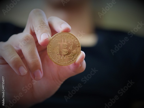 A man hold a golden coin of bitcoin(BTC). A cryptocurrency made by Satoshi Nakamoto