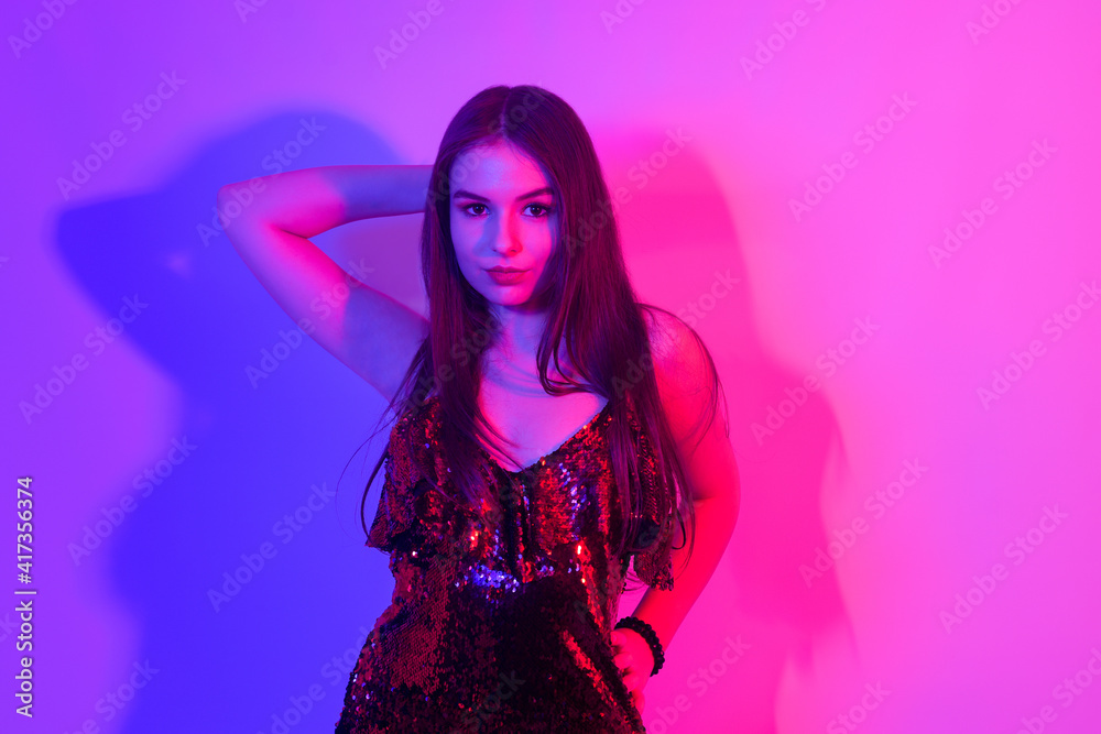 A girl in neon is dancing against a red-blue background. Hipster girl with fashionable haircut and glasses dancing, posing. Model in a fur coat at the club. A girl in neon is dancing against a red-blue background. Hipster girl with fashionable haircut and glasses dancing, posing. Model in a fur coat at the club.