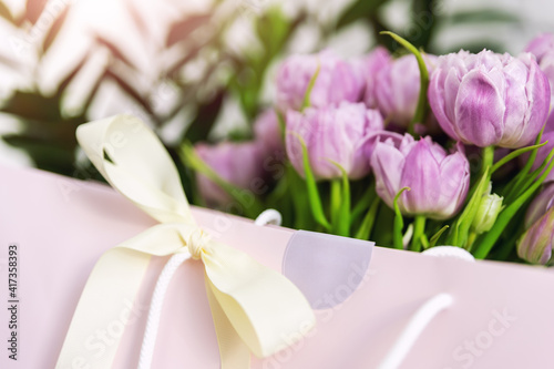 Wallpaper Mural Close-up detail of fresh beautiful present of tender violet peony tulips bouquet and paper gift bag with romantic bow. Wedding or anniversary celebration surprise background. Pastel floral decoration Torontodigital.ca